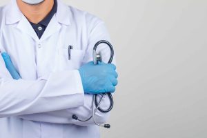 Doctor crossing arms while holding stethoscope in white coat fro